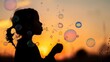 © Plaifah - A child blowing bubbles, their silhouette and the bubbles reflecting the soft light of sunset