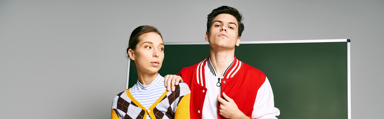 Wall Mural - Two students, a man and a woman, dressed casually, standing together in front of a green board in a college classroom.