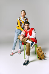 Wall Mural - Stylish male and female students striking a pose on a chair in a college classroom.