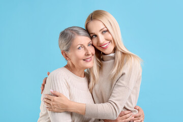 Wall Mural - Family portrait of young woman and her mother on light blue background