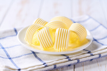 Wall Mural - Butter curls in a plate on a white wooden table, selective focus. Close-up of butter curls.