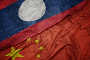 Wall Mural - waving colorful flag of laos and national flag of china on the dollar money background. finance concept.