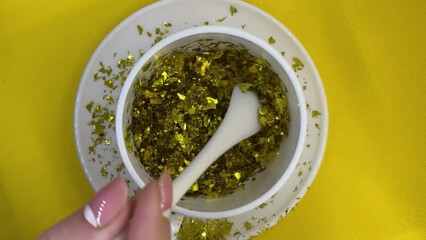 Wall Mural - A cup with gold glitter on a saucer is stirred with a spoon