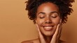 © Orod - Happy woman with radiant skin and curly hair enjoying skincare, hands on her face.