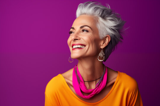 Mature middle aged stylish modern woman wearing bright colored neon cloths in bright single color background, smiling happy woman wearing stone embedded jewelries. good health with good skin care