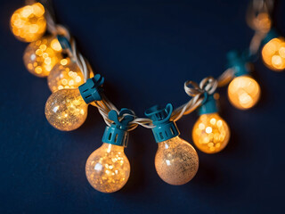 holiday illumination and decoration concept - Christmas garland bokeh lights over a dark blue background design