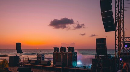 Wall Mural - A wide shot of a concert stage setup on a beach at sunset. The stage is equipped with large speakers and lighting equipment, and the ocean can be seen in the background.