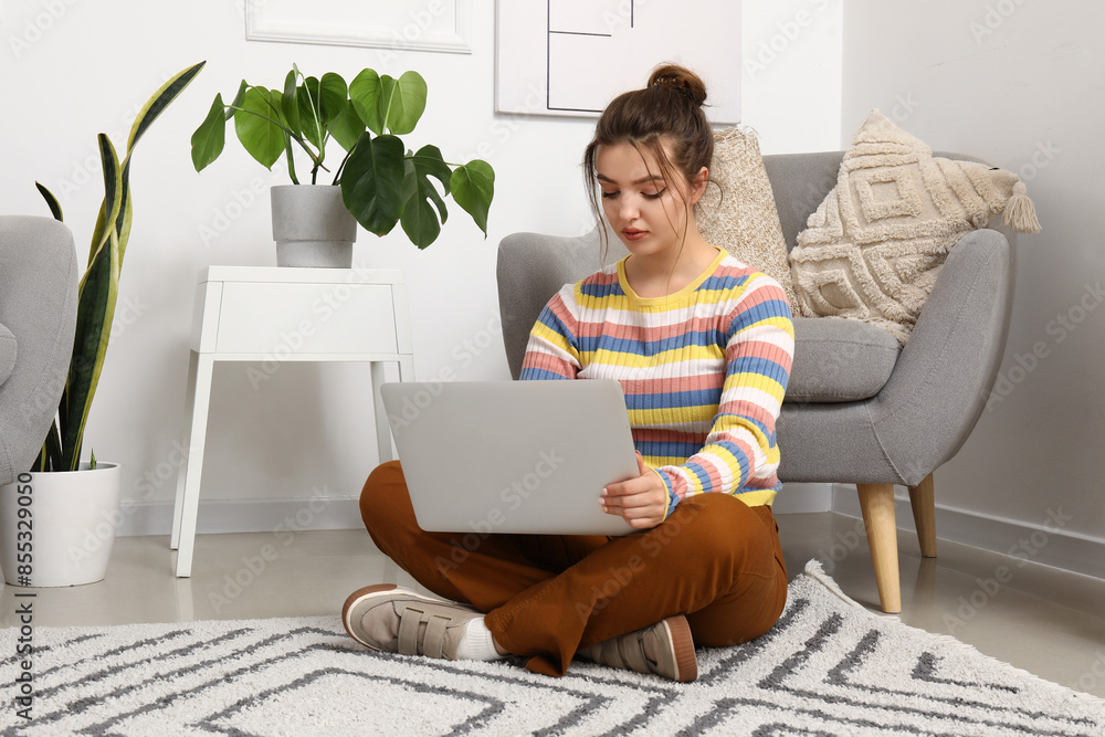 Female freelancer working with laptop on floor at home