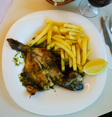 Sticker - Baked in oven dorado fish with lemon and french fries served on plate