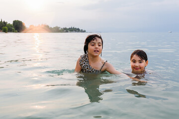 Wall Mural - two children swimming in the lake in the evening