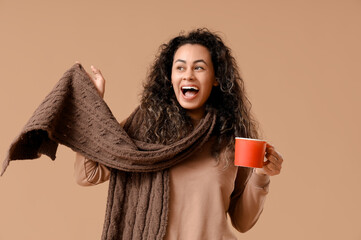 Sticker - Happy young African-American woman in scarf with cup of hot mulled wine on brown background