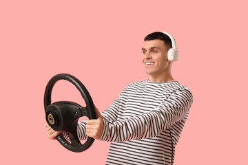 Poster - Young man in headphones with steering wheel on pink background