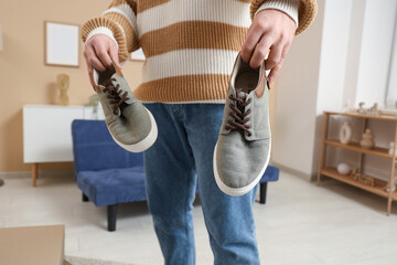 Sticker - Young man holding stylish shoes at home