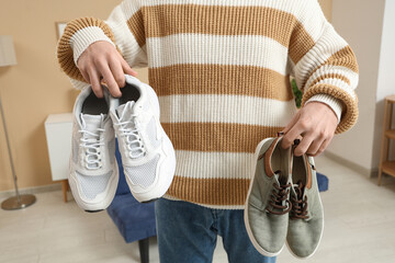 Wall Mural - Young man holding stylish shoes at home