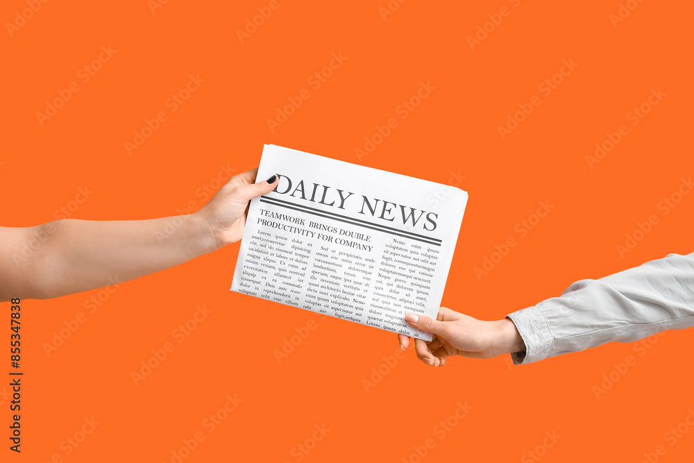 Female hands with newspaper on orange background