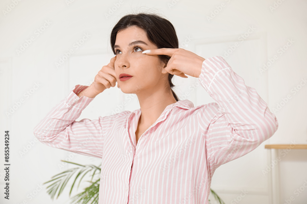 Beautiful young woman doing face building exercise in bathroom