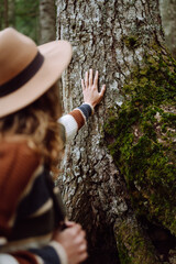 Female tourist with backpack and travel equipment touching tree while standing in the forest. Concept to love nature and tree . Environment ecology and Earth Day concept.