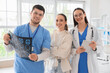 © Pixel-Shot - Smiling doctors with MRI scan and patient in clinic