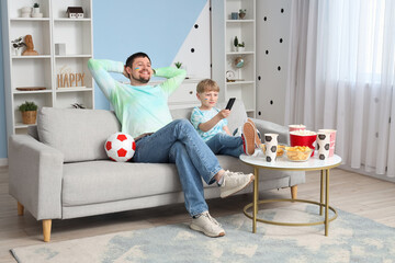 Wall Mural - Young father and little son watching football together at home