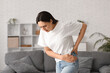 © Pixel-Shot - Young woman suffering from back pain at home