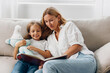 © SHOTPRIME STUDIO - Mother and daughter bonding time enjoying a story together on a cozy couch