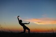 © Zenstratus - Silhouette of male ballet dancer doing a majestic dance move in nature, Behind him are heavenly clouds and the sun is setting.