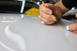 © Евгений Вершинин - A man repaints a scratch on a car part in an auto repair shop with precision and craftsmanship