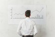 © Jeannaa - Businessman analyzing financial graph, standing in front of a whiteboard with upward trending charts, focusing on data growth and business success.