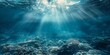 © saichon - Underwater scene with sunlight filtering through the water, creating an ethereal and tranquil atmosphere. The blue tones convey calmness as sunlight illuminates the deep ocean floor.