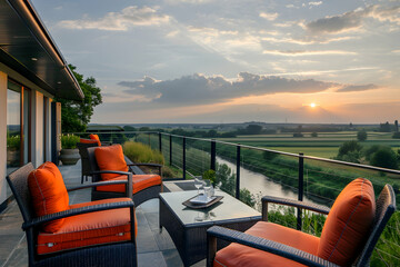 A stylish terrace with orange cushioned chairs and a glass table, offering views of a river and farmlands