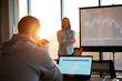 © standret - Beautiful sun beam. Female business trainer is against projector with business data, teaching the man