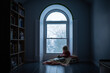© Cavan Images - Child reading by a window on snowy day, blankets and bookshelves