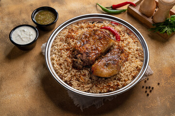 Delicious colorful Afghan rice pilaf Kabuli pulao with lamb or Chicken and raisin, carrot, nut, spices closeup on the plate on the wooden table.