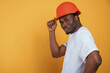 © standret - In orange hard hat. Construction worker. Handsome black man is in the studio against yellow background