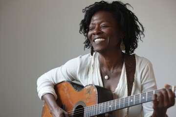 Wall Mural - Portrait of a joyful afro-american woman in her 40s playing the guitar isolated in minimalist or empty room background