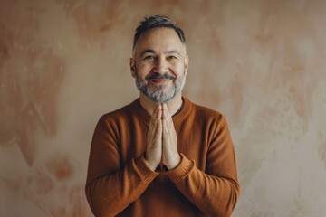 Wall Mural - Portrait of a jovial man in his 40s joining palms in a gesture of gratitude on minimalist or empty room background