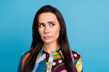 Poster - Photo of attractive young woman look sad skeptical empty space dressed stylish colorful print clothes isolated on blue color background