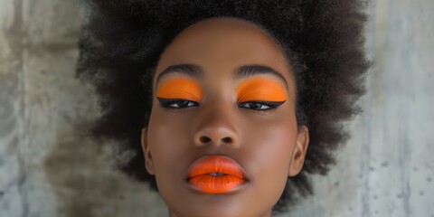 Wall Mural - An African model with vibrant makeup and orange accents poses stylishly, showcasing her glamorous look.