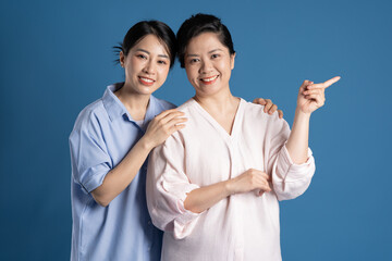 Wall Mural - Image of an Asian mother and child posing on a blue background.