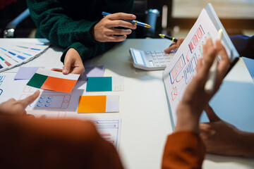 UX developer and ui designer brainstorming about mobile app interface wireframe design with customer breif and color code at office.