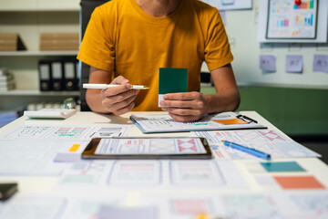 UX developer and ui designer brainstorming about mobile app interface wireframe design with customer breif and color code at office.