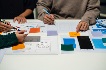 UX developer and ui designer brainstorming about mobile app interface wireframe design with customer breif and color code at office.