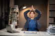 © Wasana - A woman in a blue suit is sitting at a desk with a laptop and a stack of papers