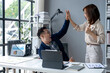 © Wasana - A man and a woman are high fiving each other in a cubicle