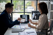 © Wasana - Two people are sitting at a desk with a laptop and a calculator