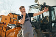 © standret - Communication with other people by walkie talkie. Man is with tractor. Agricultural worker