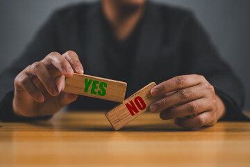 Wall Mural - businessman holding the wooden block shows yes or no letters.