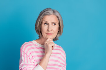 Poster - Photo portrait of attractive retired woman look empty space skeptical dressed stylish striped clothes isolated on blue color background