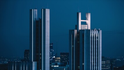 There are four skyscrapers in the photo. They are illuminated by a blue light.

