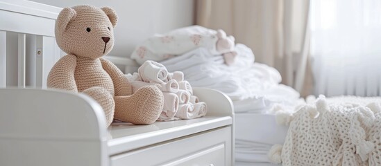 Modern designed white cozy corner with cradle for little baby. On the night stand teddy bear and baby's clothes. Copy space image. Place for adding text and design
